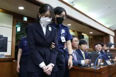 어두운 색 정장을 입고 마스크를 쓴 김건희 씨가 법정 안에서 경찰의 부축을 받으며 이동하고 있다. 