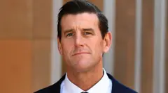Ben Roberts-Smith olha para a câmera, vestindo um terno.