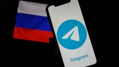 يظهر شعار تطبيق تيليغرام على شاشة هاتف ذكي، فيما يظهر العلم الروسي في الخلفية على شاشة حاسب آلي. وكانت السلطات الروسية قد أعلنت فرض قيود تدريجية على الوصول إلى تطبيق المراسلة، متهمةً إياه بعدم حجب المحتوى غير القانوني، وذلك في مدينة تورينو الإيطالية بتاريخ 24 فبراير/شباط 2026.