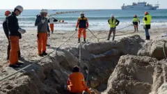 Cabos submarinos de fibra óptica sendo aterrados em praia