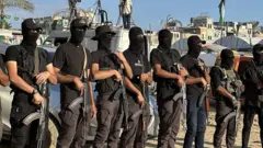 Бойцы ХАМАС сна улице в секторе Газа. Они в балаклавах и вооружены автоматами.