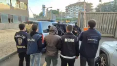 polis ekipleri birilerini gözaltına alıyor