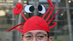 2026年3月11日，在北京百度总部，一名男子戴着印有开源人工智慧助理OpenClaw标志的龙虾帽。 