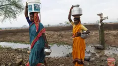 पाण्याचा हंडा डोक्यावर घेतलेल्या महिला 