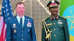 ሰማያዊ ወተሃደራዊ ክዳን ዝለበሰ ኣመሪካዊ ጀነራል ምስ ምሉእ መዓርጉ ዝለበሰ ኢታማጆር ሹም ኢትዮጵያ ብርሃኑ ጁላ