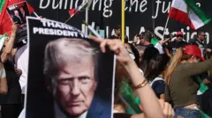 Pessoas em Los Angeles agitam bandeiras e cartazes com a imagem de Trump em apoio aos ataques contra o Irã.