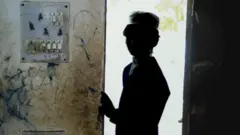 ਬੱਚਾ ਖੜ੍ਹਾ ਹੈ ਪਰ ਉਸਦਾ ਚਿਹਰਾ ਨਹੀਂ ਦਿਖਾਇਆ ਗਿਆ ਹੈ