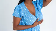 Plus size female model pose in blue dress on gray background, young African fat woman wit curvy figure and pigtail hairstyle