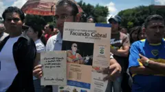 Un manifestante sostiene un cartel con la foto de Facundo Cabral y el anuncio de su concierto, durante una protesta en Guatemala