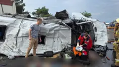 Люди стоять поряд з перевернутим мікроавтобусом