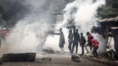 Protesters react as Kenya police officers fire tear gas during clashes at Saba Saba Day demonstrations in Nairobi on July 7, 2025