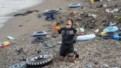 Migrantes y personas llegadas por vía marítima tras cruzar la frontera entre Marruecos y Ceuta, el 31 de julio de 2026, en Ceuta, España. En la imagen de ve un hombre arrodillado que parece estar agradeciéndole al cielo.