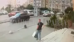 Umugabo wambaye ipantalo y'ikoboyi n'umupira wijimye w'amaboko magufi afite igikapu gito cya plastike n'ikindi gikapu kijyamo ibintu binyuranye, atwaye ibikapu byombi mu kuboko kumwe, arimo kugenda ava mu nyubako, yerekeza ahaparikwa imodoka, i Kyiv, muri Ukraine. 