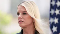 Pam Bondi com a bandeira dos EUA ao fundo