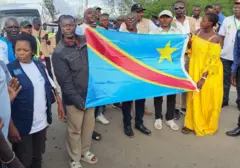 Umugabo n'umugore bari mu batashe bafashe ibendera ry'igihugu cabo bageze ku rubibe rw'Uburundi na RD Congo