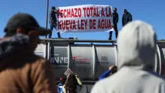 Camioneros que transportan mercancías de exportación a Estados Unidos sostienen una pancarta que dice "Rechazo total a la nueva ley del agua" Durante una manifestación como parte de la huelga nacional de agricultores, en el Puente Internacional Zaragoza-Ysleta en Ciudad Juárez, estado de Chihuahua, México, el 24 de noviembre de 2025. (Foto de HERIKA MARTINEZ / AFP vía Getty Images)