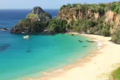 Praia com água turquesa e penhascos