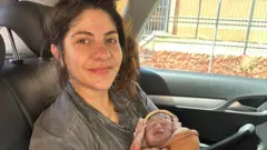 Lais segurando o filho logo após o nascimento dentro de um veículo