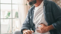 Homme avec la main sur le ventre en signe d'inconfort.