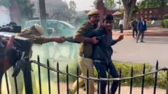 धुआं छोड़ने वाले को पकड़ते पुलिसकर्मी