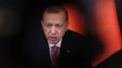 الرئيس التركي رجب طيب أردوغان يرتدي بدلة سوداء وربطة عنق حمراء منقوشة أزرق ويبدو أنه يتحدث في لقاء عام
