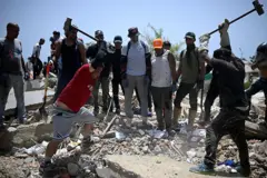 Voluntários golpeiam restos de concreto com marretas de ferro em busca de sobreviventes sob os escombros em La Guaira, Venezuela, 26 de junho de 2026