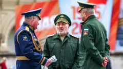 Руслан Цаликов на репетиции парада в мае 2024 года. Он стоит в окружении двух других генералов. На нем военная форма, на лице щетина