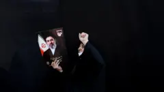 امرأة تحمل لافتة عليها صورة المرشد الأعلى الإيراني الجديد مجتبى خامنئي، خلال تجمع لدعمه في طهران، إيران، 9 مارس/آذار 2026