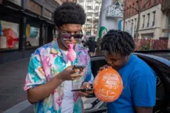 Dos jóvenes con globos en la boca en Reino Unido. 