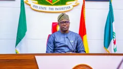 Gómìnà Seyi Makinde jòkòó lórí àga, wọ aṣọ olómi aro, ó gbé gbohùngbohùn síwájú