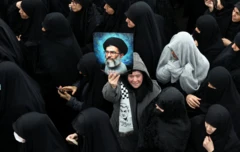 İranlı bir kadın, 18 Mart'ta öldürülen İran İstihbarat Bakanı İsmail Hattab ve ailesinin cenaze törenine katılırken, merhum İran dini lideri Ayetullah Ali Hamaney'nin fotoğrafını tutuyor. 