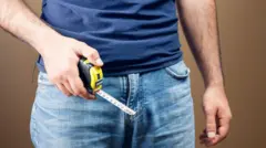 Homem segurando fita métrica no púbis