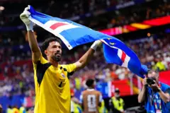 Vozinha com uma bandeira de Cabo Verde após jogo. Ele usa um uniforme amarelo.