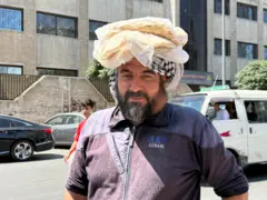 رجل سوري يحمل ربطة خبز على رأسه.