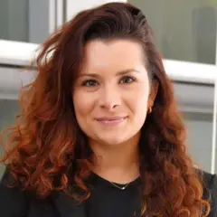 Micaela Rodriguez sorrindo contidamente em frente a janela