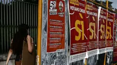 Женщина проходит мимо плакатов в поддержку референдума в центре Рима.