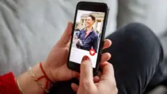 Mão segurando celular com aplicativo Tinder aberto