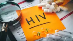 A paper wey dem write HIV ontop wit drugs and magnifier beside am