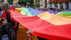 Uczestnicy marszu równości w Polsce trzymają flagę LGBTQ w Krakowie