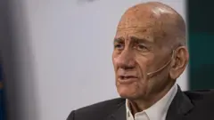 Ehud Olmert con una chaqueta oscura y una camisa blanca.