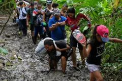 Un grupo de migrantes camina por un estrecho fangoso en el Darién