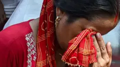 Une femme essuie ses larmes avec son voile.
