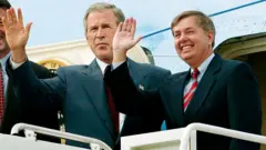 Graham sonríe y saluda mientras sube a un avión con Bush.