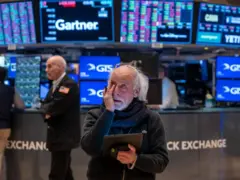 Pessoa com olhar atônito na bolsa de valores, observando a oscilação dos preços das ações