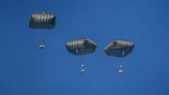 ग़ज़ा में मंगलवार को मिस्र की वायु सेना की ओर से पैराशूट से गिराई गई राहत सामग्री