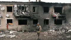 Um soldado ucraniano inspecionando um edifício destruídoslot apostasVovchansk