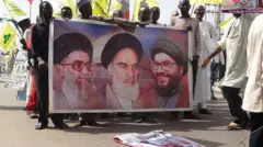 Group of Nigerians wey dey hold poster wey get picture of di Iran Ayatollah Ali Khamenei for 2014 protests
