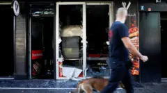 Мужчина смотрит на разрушенный турецкий ресторан, выгуливая собаку в центре города.