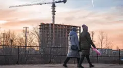 Прохожие на фоне строящегося жилого дома