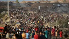 Palestinians gather at an aid distribution point set up by the privately-run Gaza Humanitarian Foundation (GHF), near the Nuseirat refugee camp in the central Gaza Strip on June 25, 2025. 
